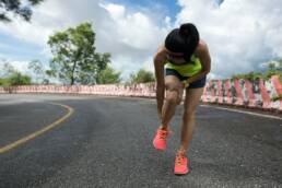 Woman runner suffering with pain on sports running knee injury