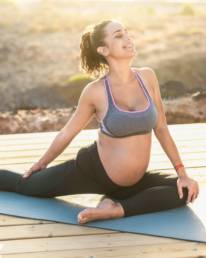 Young pregnant woman doing prenatal pilates exercises session outdoor