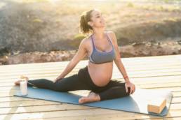 Young pregnant woman doing prenatal pilates exercises session outdoor